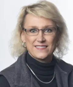 A woman with blonde hair wearing glasses and a black shirt.