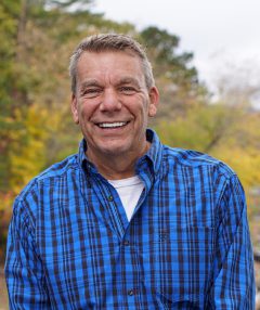 A man in blue shirt smiling for the camera.