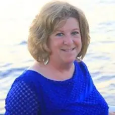 A woman in blue shirt standing next to water.